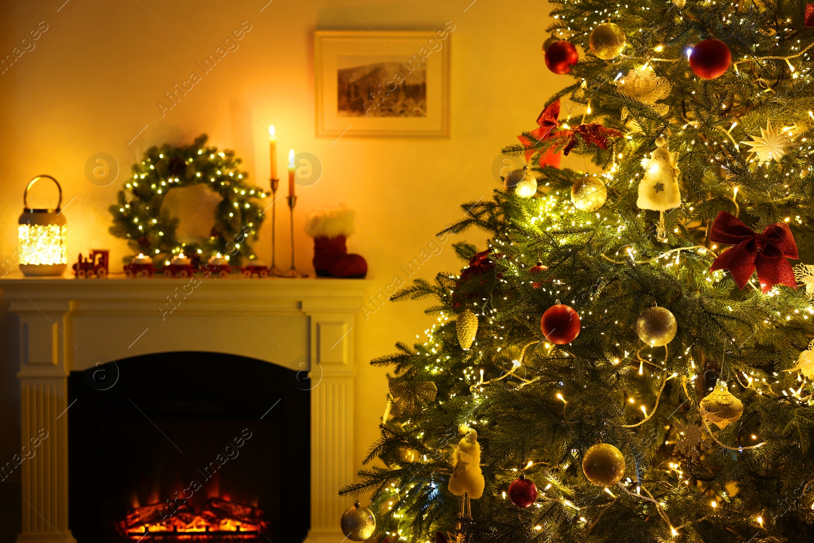 Photo of Decorated Christmas tree near fireplace in room. Festive interior design