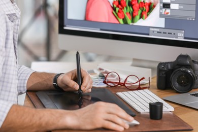 Photo of Professional retoucher working on graphic tablet at table, closeup