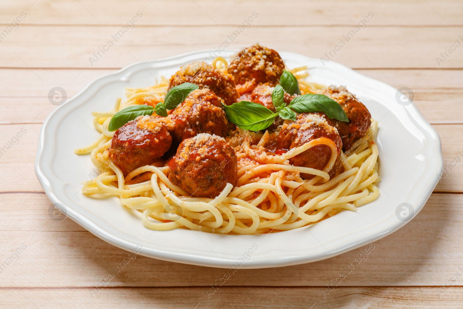 Photo of Delicious pasta with meatballs on light wooden table, closeup