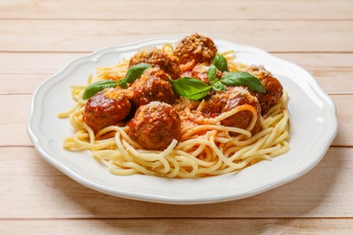 Delicious pasta with meatballs on light wooden table, closeup