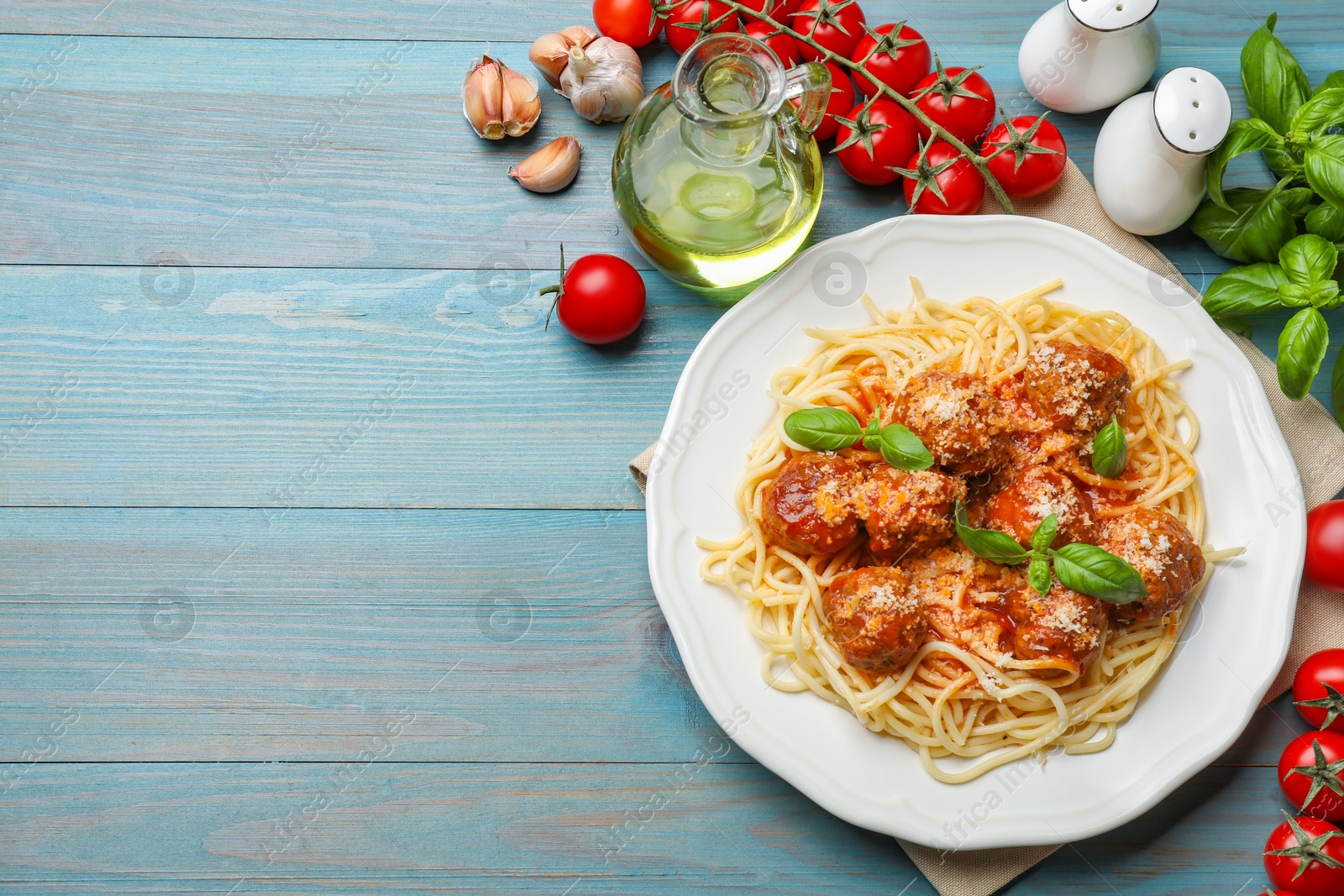 Photo of Delicious pasta with meatballs and ingredients on light blue wooden table, flat lay. Space for text