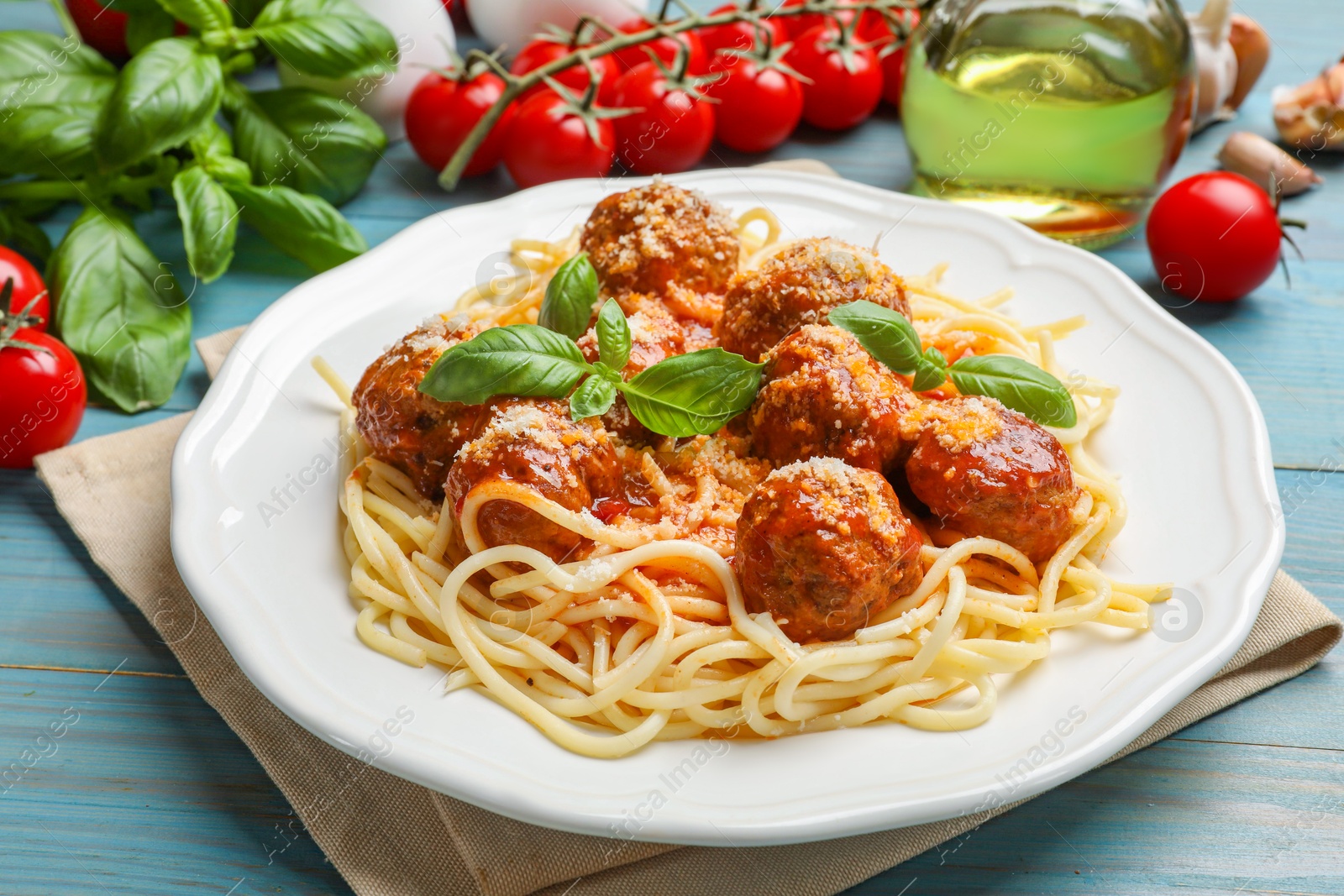 Photo of Delicious pasta with meatballs and ingredients on light blue wooden table, closeup