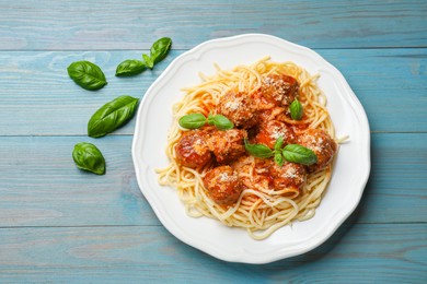 Delicious pasta with meatballs on light blue wooden table, top view