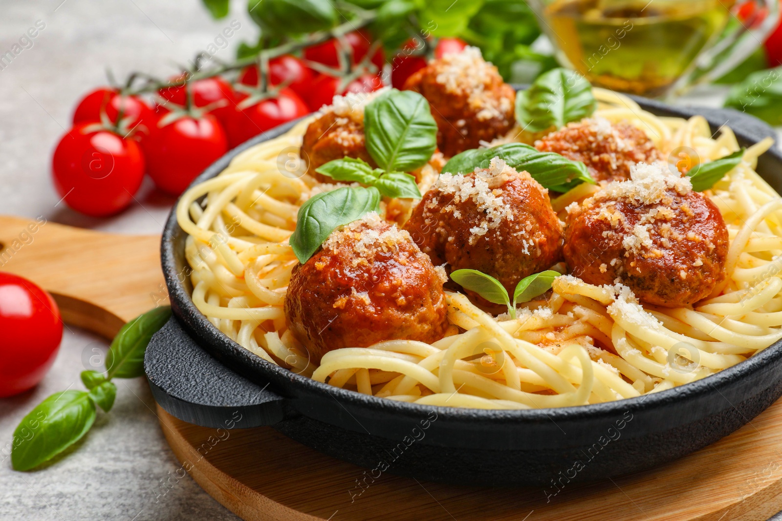 Photo of Delicious pasta with meatballs and ingredients on light grey table, closeup