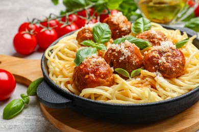 Delicious pasta with meatballs and ingredients on light grey table, closeup