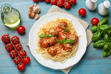 Photo of Delicious pasta with meatballs and ingredients on light blue wooden table, flat lay