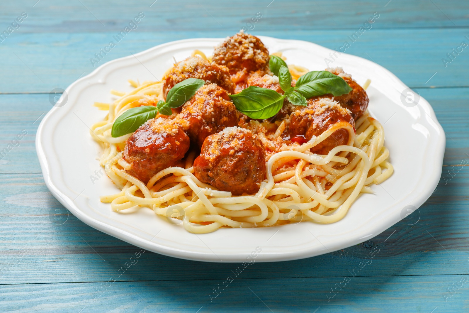 Photo of Delicious pasta with meatballs on light blue wooden table, closeup