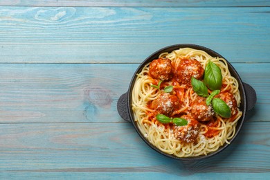 Photo of Delicious pasta with meatballs on light blue wooden table, top view. Space for text