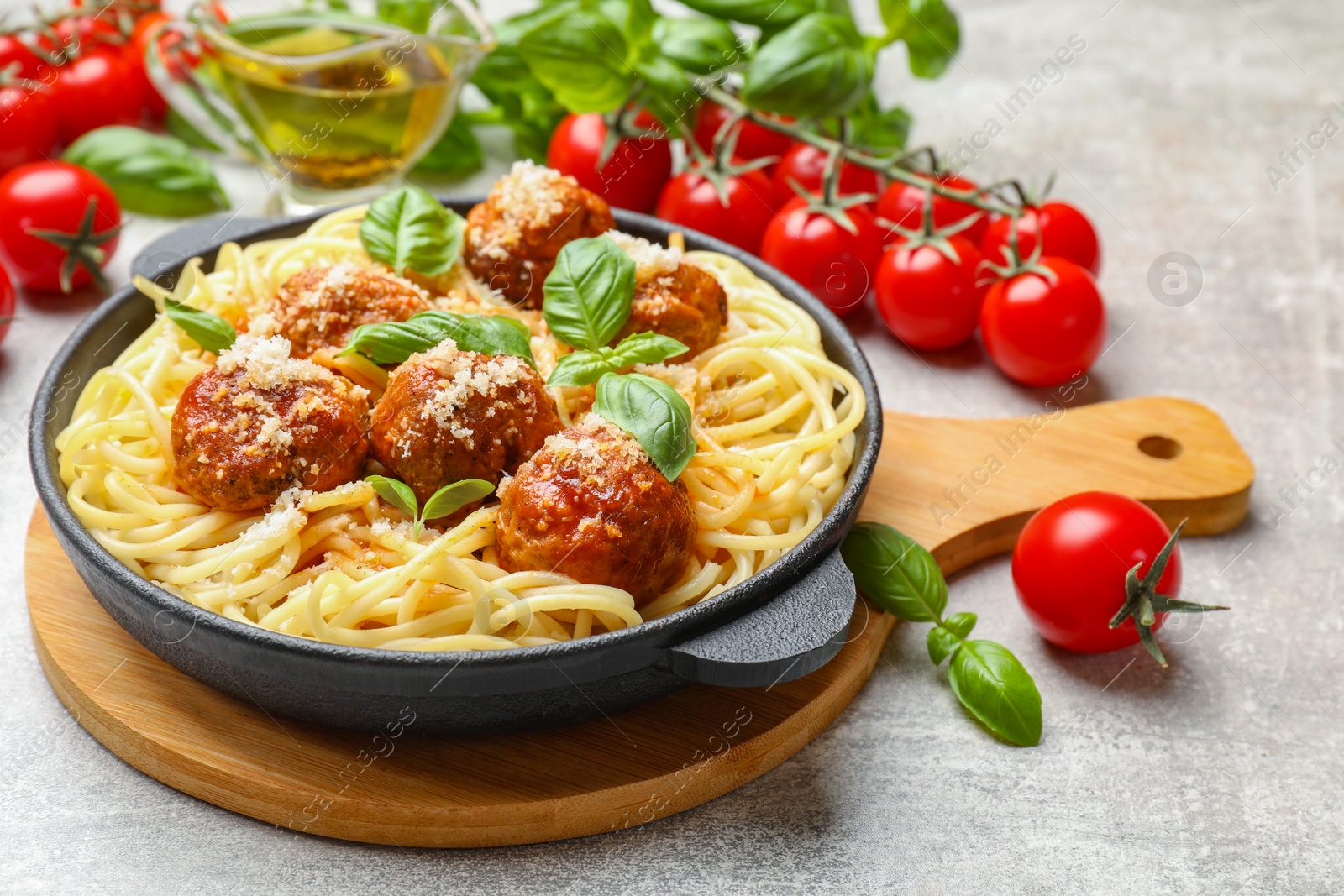 Photo of Delicious pasta with meatballs and ingredients on light grey table, closeup