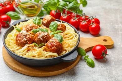 Delicious pasta with meatballs and ingredients on light grey table, closeup