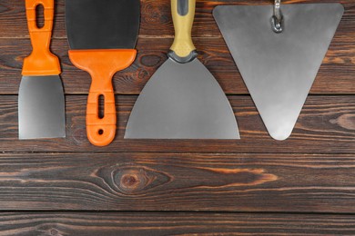 Photo of Putty knives on wooden table, flat lay with space for text. Construction tools