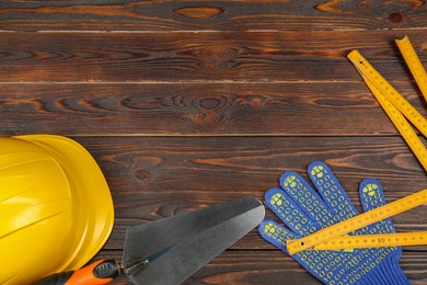 Different construction tools and safety equipment on wooden table, flat lay. Space for text