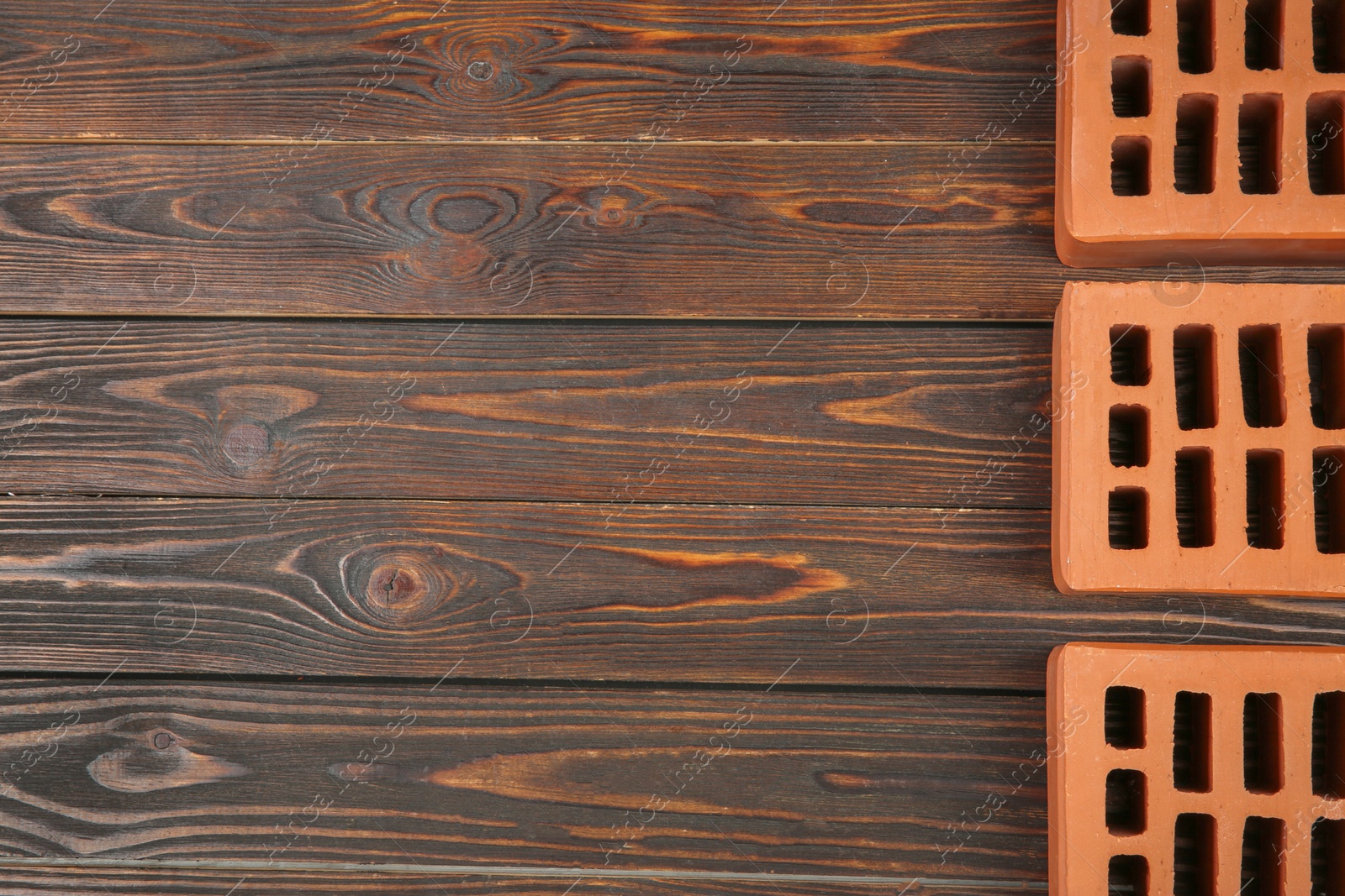 Photo of Many red bricks on wooden table, flat lay with space for text. Building material