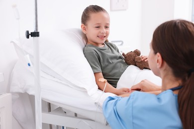 Photo of Doctor examining little girl on bed at hospital