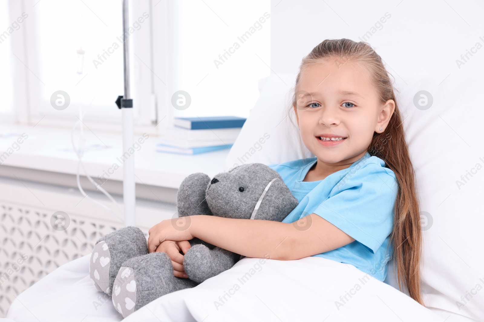 Photo of Cute little girl with toy bunny on bed in hospital