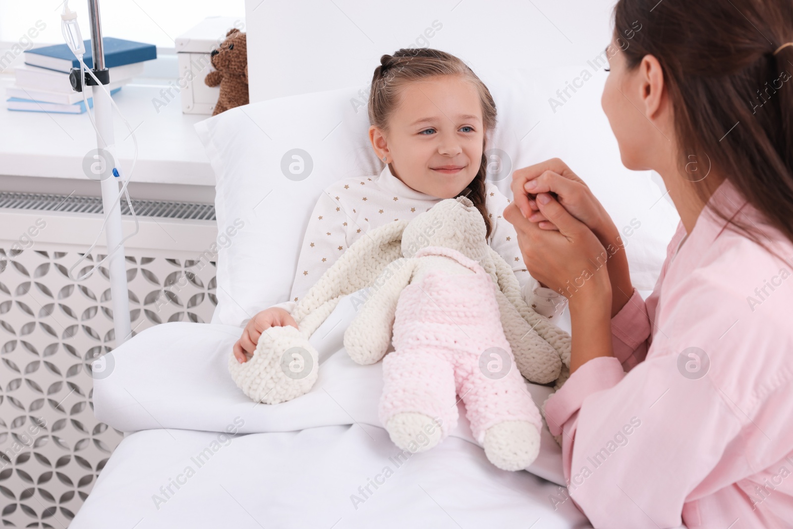 Photo of Mother and her little daughter on bed in hospital