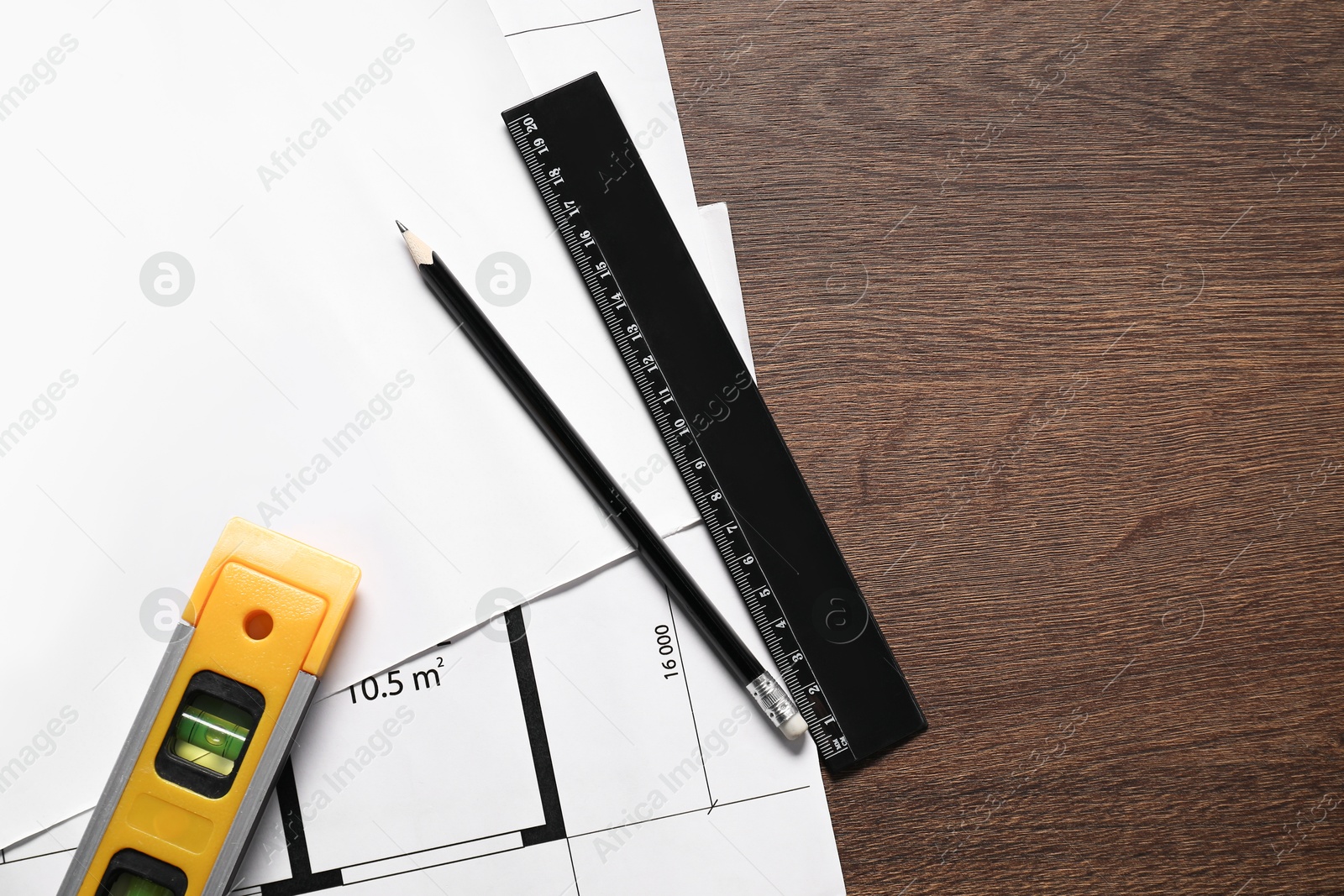 Photo of Different architectural drawings, building level, pencil and ruler on wooden table, top view