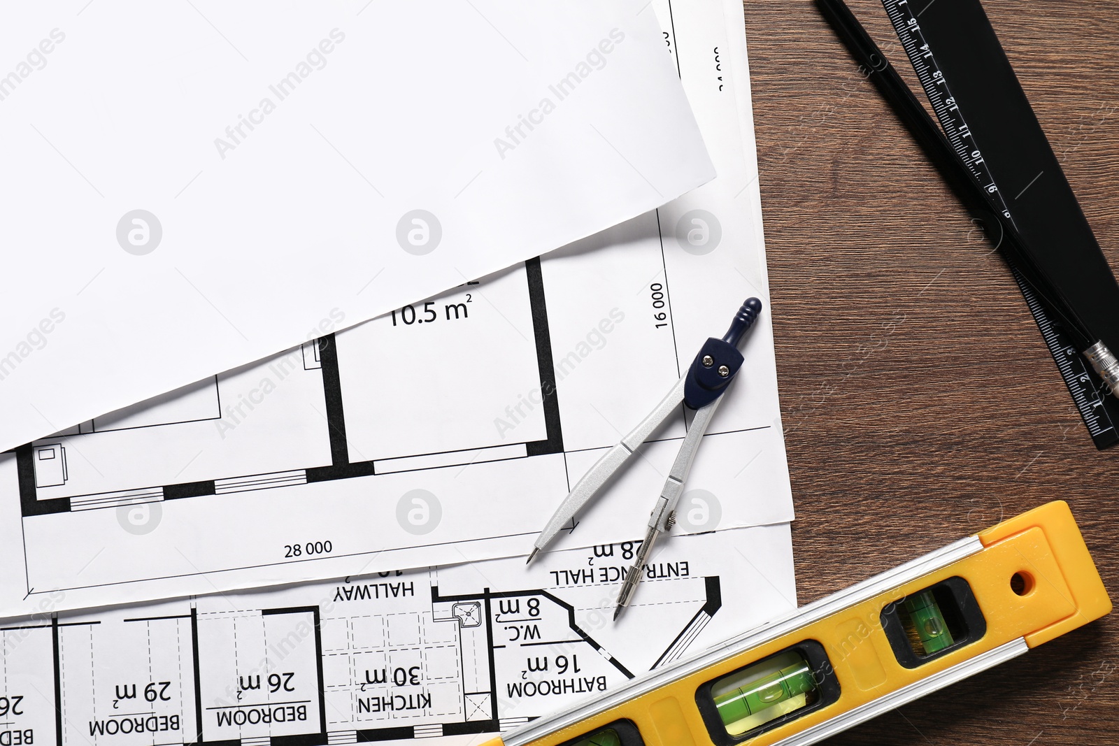 Photo of Different architectural drawings, dividers, building level, pencil and ruler on wooden table, flat lay