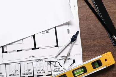 Photo of Different architectural drawings, dividers, building level, pencil and ruler on wooden table, flat lay