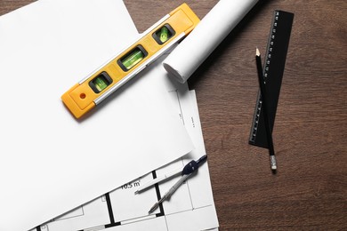 Photo of Different architectural drawings, dividers, building level, pencil and ruler on wooden table, flat lay