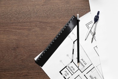 Photo of Different architectural drawings, pencil and dividers on wooden table, flat lay