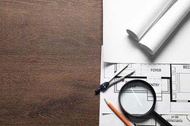 Photo of Different architectural drawings, pencil, magnifying glass and dividers on wooden table, top view. Space for text