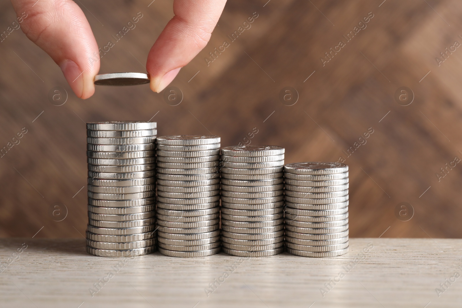 Photo of Woman putting coins at light wooden table, closeup. Salary concept