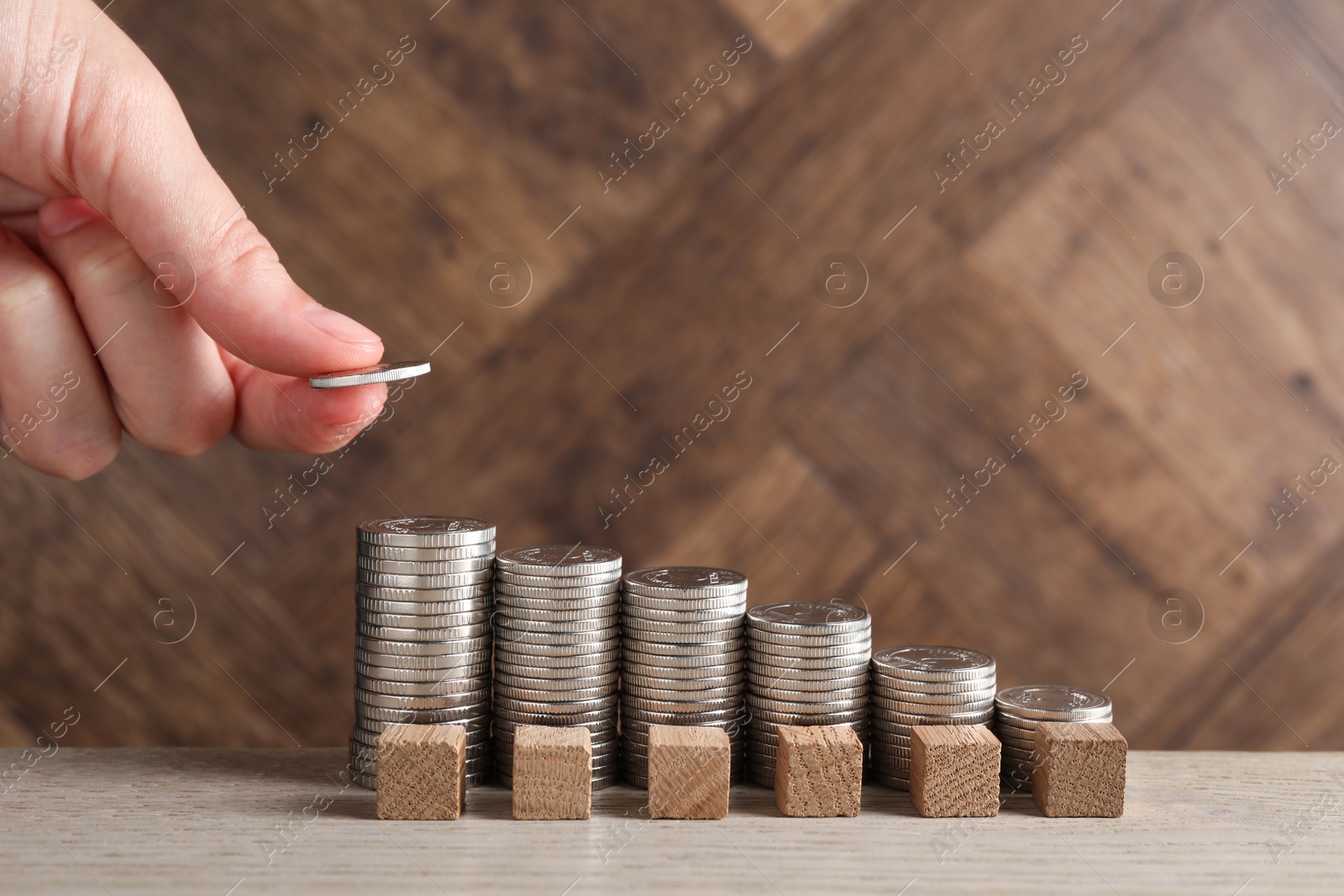 Photo of Woman putting coins at light wooden table, closeup. Salary concept