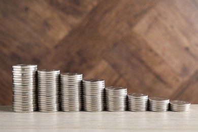 Photo of Stacked coins on light wooden table, closeup with space for text. Salary concept