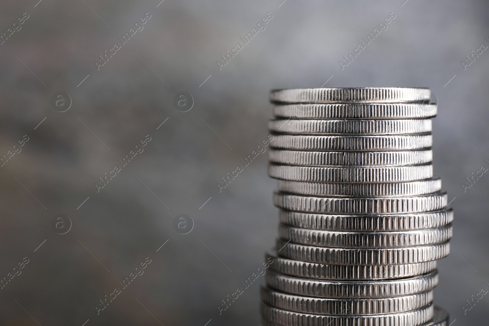 Photo of Stack of coins on blurred grey background, closeup with space for text. Salary concept