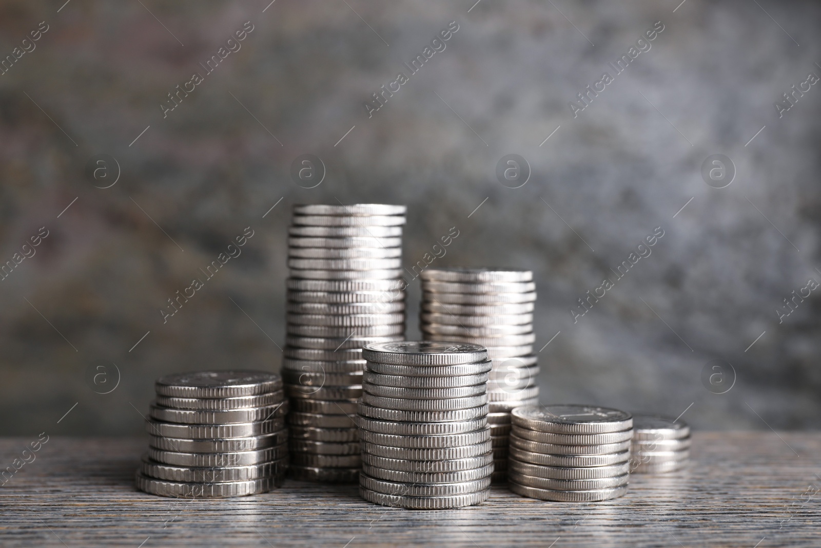 Photo of Stacked coins on wooden table against blurred grey background, closeup. Salary concept