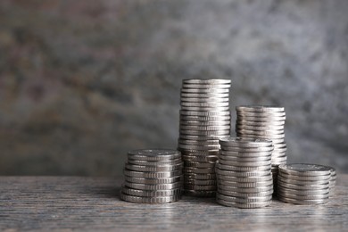 Photo of Stacked coins on wooden table against blurred grey background, closeup with space for text. Salary concept