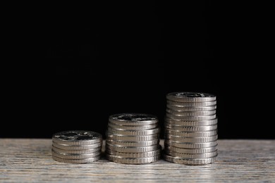 Photo of Stacked coins on wooden table against black background, closeup. Salary concept