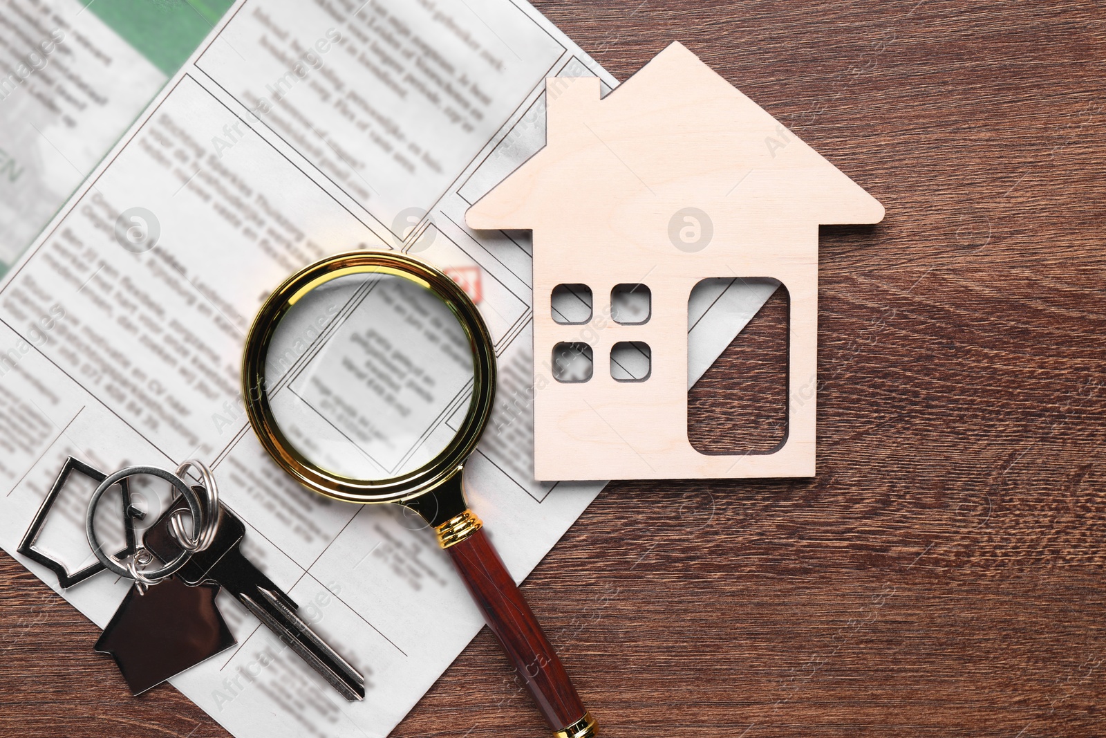 Photo of House hunting. Magnifying glass, keys, house figure and newspaper on wooden table, flat lay