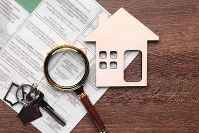 Photo of House hunting. Magnifying glass, keys, house figure and newspaper on wooden table, flat lay