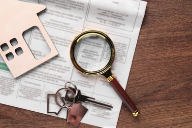 House hunting. Magnifying glass, keys, house figure and newspaper on wooden table, flat lay