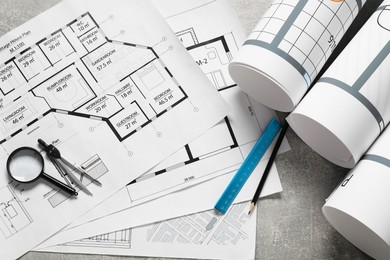 Photo of Different engineering drawings and tools on grey textured table, flat lay