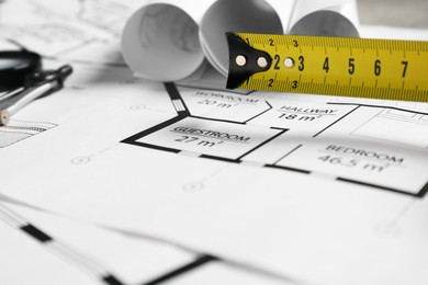 Photo of Different architectural drawings and measuring tape on table, closeup