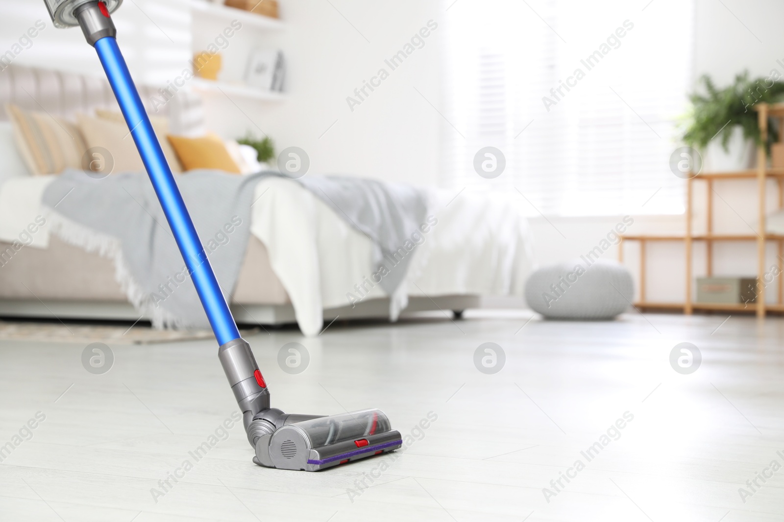 Photo of Cleaning floor with cordless vacuum cleaner indoors, closeup. Space for text