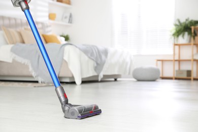 Photo of Cleaning floor with cordless vacuum cleaner indoors, closeup. Space for text