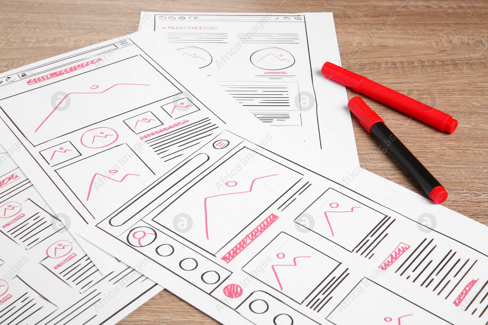 Photo of Developing UI design. Sketches of website wireframes and felt pens on wooden table, closeup