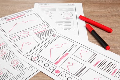 Photo of Developing UI design. Sketches of website wireframes and felt pens on wooden table, closeup