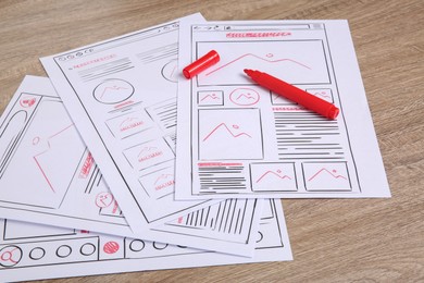 Photo of Developing UI design. Sketches of website wireframes and felt pen on wooden table, closeup