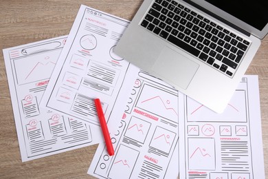 Developing UI design. Sketches of website wireframes, laptop and felt pen on wooden table, top view