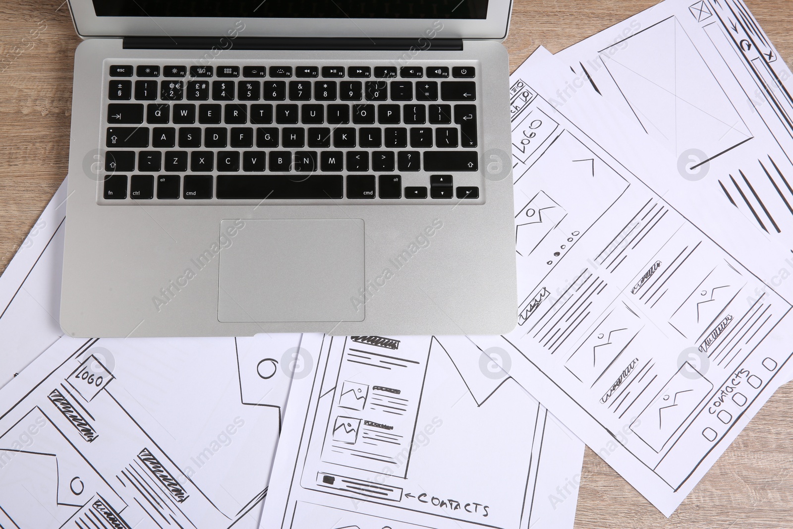 Photo of Developing UI design. Sketches of website wireframes and laptop on wooden table, top view