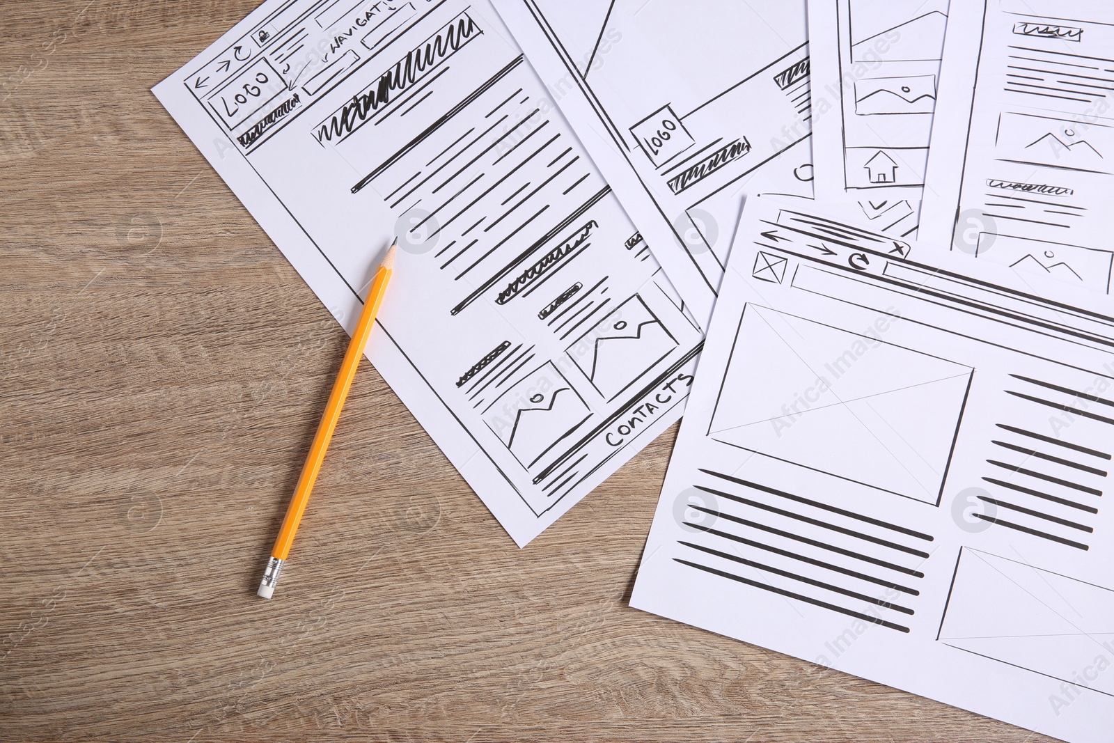 Photo of Developing UI design. Sketches of website wireframes and pencil on wooden table, top view