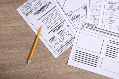 Developing UI design. Sketches of website wireframes and pencil on wooden table, top view