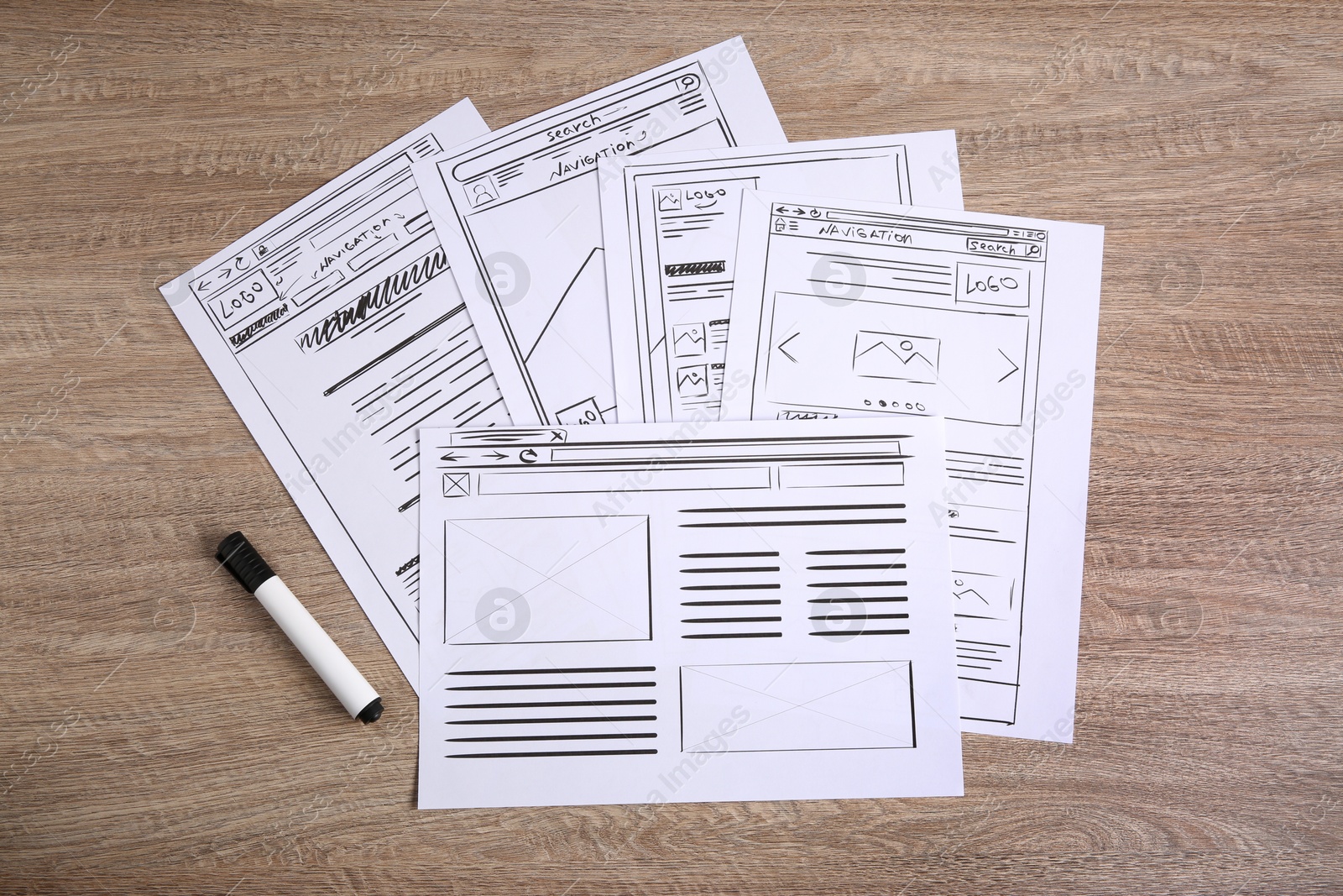 Photo of Developing UI design. Sketches of website wireframes and felt pen on wooden table, top view