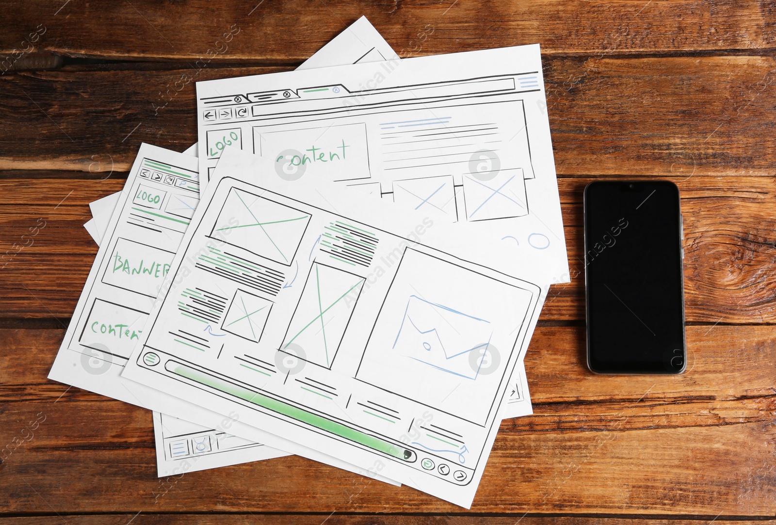 Photo of Developing UI design. Sketches of website wireframes and smartphone on wooden table, top view