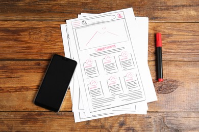 Developing UI design. Sketches of website wireframes, felt pen and smartphone on wooden table, top view